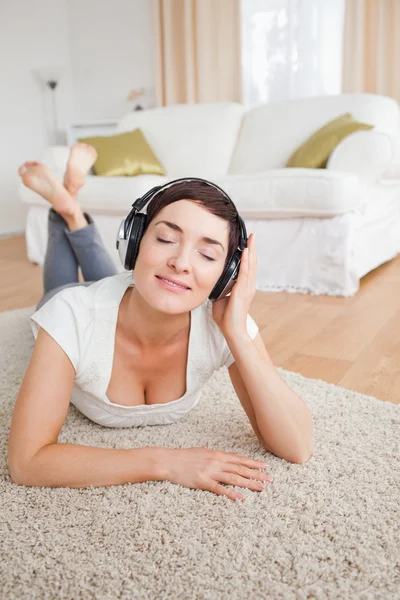Portrait of a delighted brunette listening to music — Stock Photo, Image