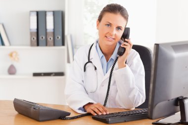 Serious female doctor on the phone clipart