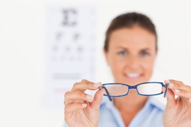 Portrait of a brunette eye specialist handing out glasses smilin clipart