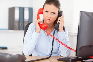 Secretary telephoning with two telephones clipart