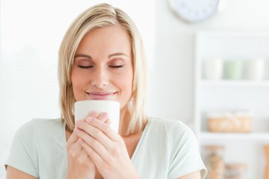 Close up of a woman taking in smell of coffee with her eyes clos clipart