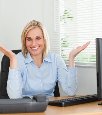 Smiling woman sitting behind desk not having a clue what to do n clipart