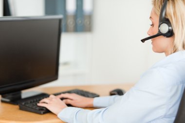 Close up of a blonde businesswoman with headset working with com clipart