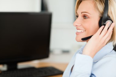 Portrait of a smiling blonde businesswoman with headset working clipart
