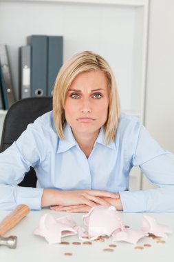 Sulking woman sitting in front of an shattered piggy bank lookin clipart