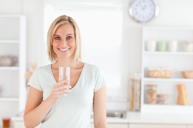 Charming woman holding glass filled with water while standing lo clipart