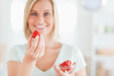 Close up of a woman enjoying eating strawberries looking into th clipart