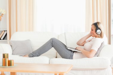 Smling woman watching a movie with her laptop clipart