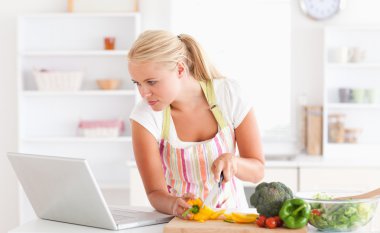 Woman using a laptop to cook clipart