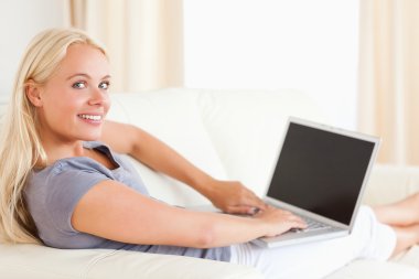 Smiling woman using a laptop clipart