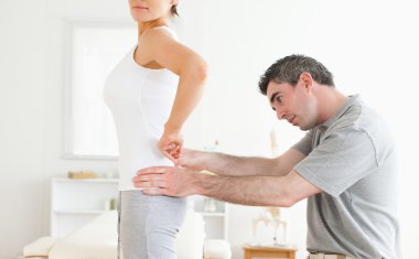 Chiropractor examining a cute woman's back clipart