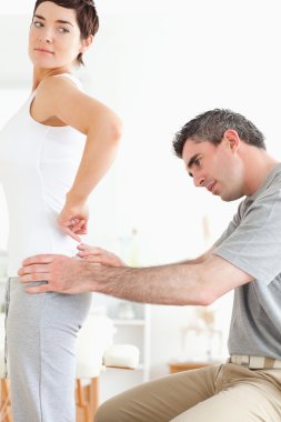 Chiropractor examining a brunette woman's back clipart