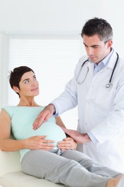 Doctor examining a pregnant woman's tummy clipart