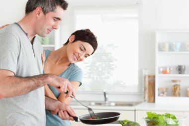 Woman looking into a pan her husband is holding clipart