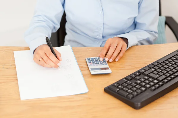 Vrouwelijke boekhouder resultaten schrijven op een stuk papier — Stockfoto