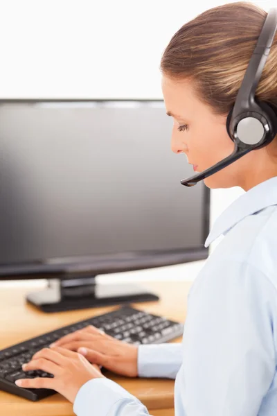 Secretaris met een headset werkt op haar computer — Stockfoto