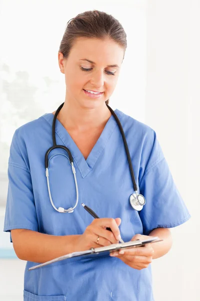 Krankenschwester schreibt mit Stift in einen Ordner — Stockfoto