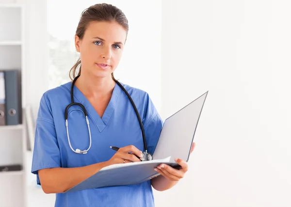 Doktor drží otevřenou složku a s stetoskop kolem on — Stock fotografie