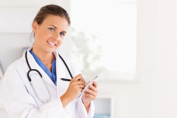 Concentrated doctor writing something down looking into the came — Stock Photo, Image
