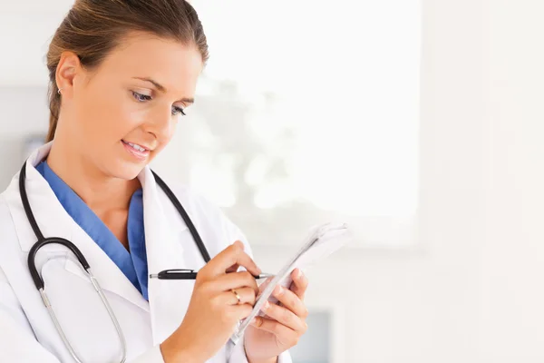 Close up of a smiling brunette doctor writing something down — Stock Photo, Image