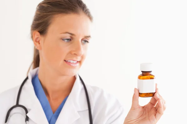 Портрет улыбающегося врача, смотрящего на таблетки — стоковое фото