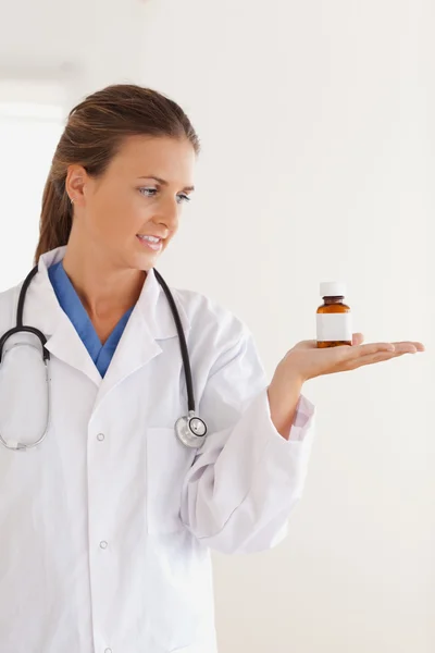 Gut aussehende brünette Ärztin schaut sich einige Pillen an — Stockfoto