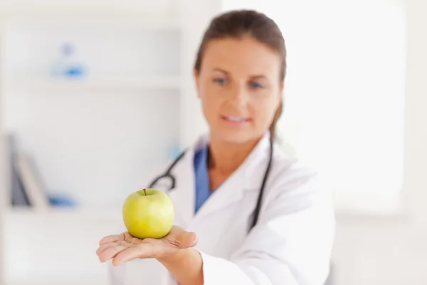 Доктор со стетоскопом смотрит на яблоко — стоковое фото