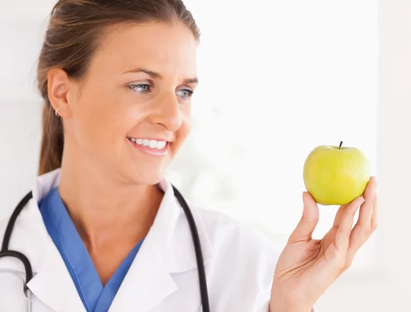 Primo piano di un medico sorridente con stetoscopio guardando un appl — Foto Stock