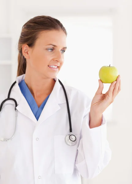 Prachtige arts kijken naar een groene appel — Stockfoto