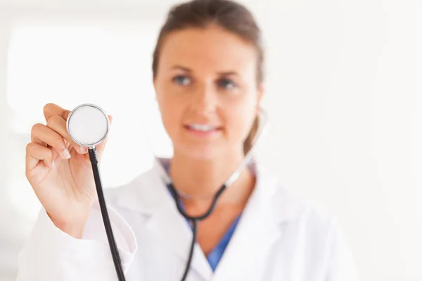 Vacker brunett läkare visar stetoskop till kameran — Stockfoto