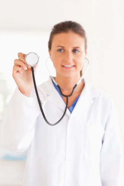 Lächelnder Arzt präsentiert ein Stethoskop und blickt in die Kamera — Stockfoto