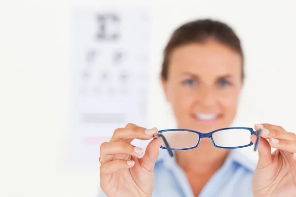 Portrait of a brunette eye specialist handing out glasses smilin — Stock Photo, Image