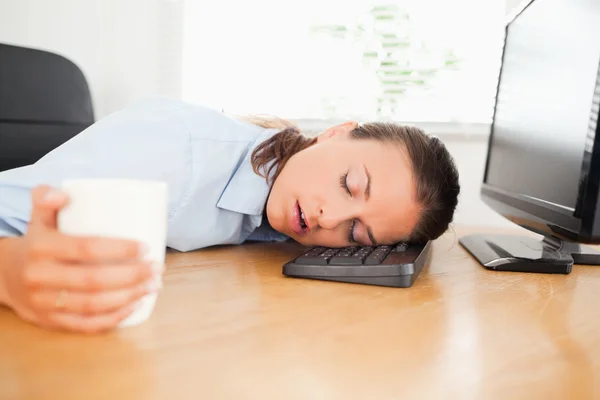 Спящая женщина в офисе держит кофе — стоковое фото