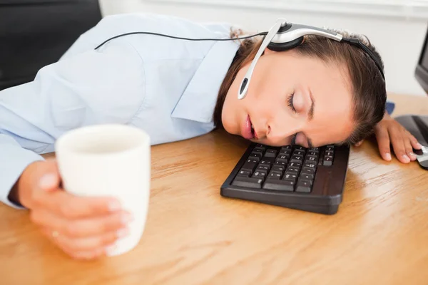Mujer de negocios con auriculares durmiendo en la oficina con café —  Fotos de Stock