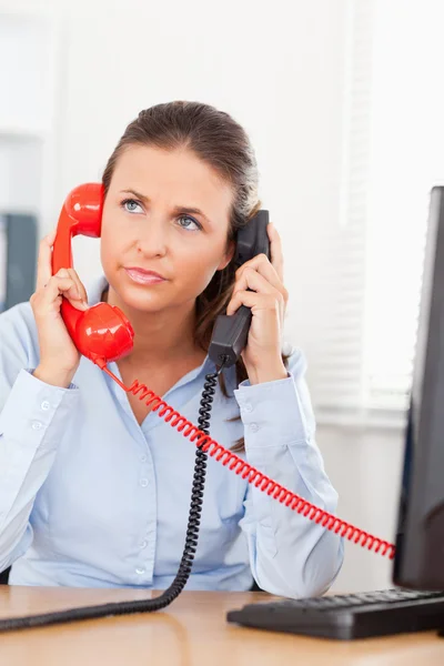 Businesswoman telephoning with two telephones — Stock Photo, Image