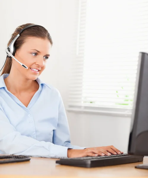 An operator with headset is typing in an office — Stock Photo, Image