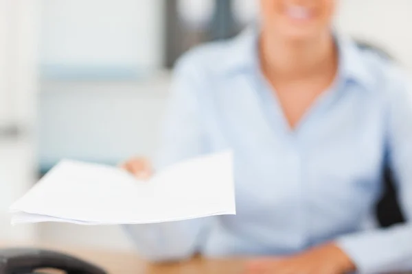 Smiling businesswoman handing out a paper — Stock Photo, Image