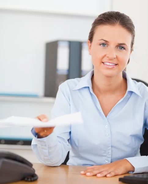 Charming brunette businesswoman handing out a paper — Stock Photo, Image