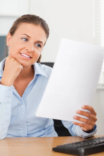 Charming businesswoman smiling at a paper — Stock Photo, Image