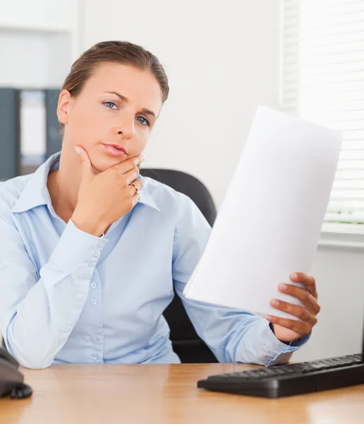 Close up of a thinking businesswoman holding a paper — Stock Photo, Image