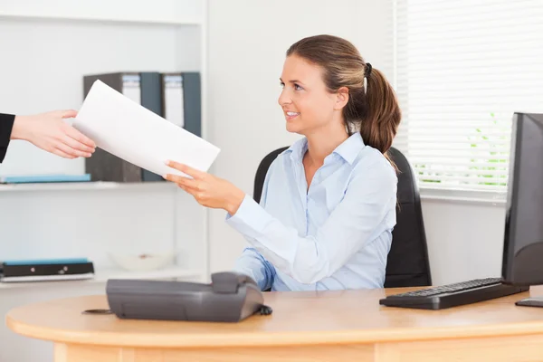 Smiling businesswoman receiving a pile of paper — Stock Photo, Image