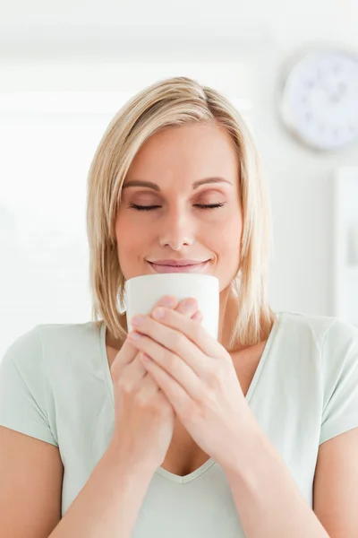 Woman taking in smell of coffee with eyes closed — Stock Photo, Image
