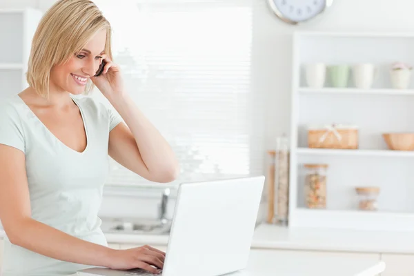 Mulher com um laptop e um telefone em busca na internet — Fotografia de Stock