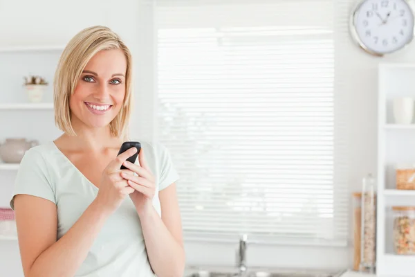 Очаровательная женщина с мобильным телефоном смотрит в камеру — стоковое фото