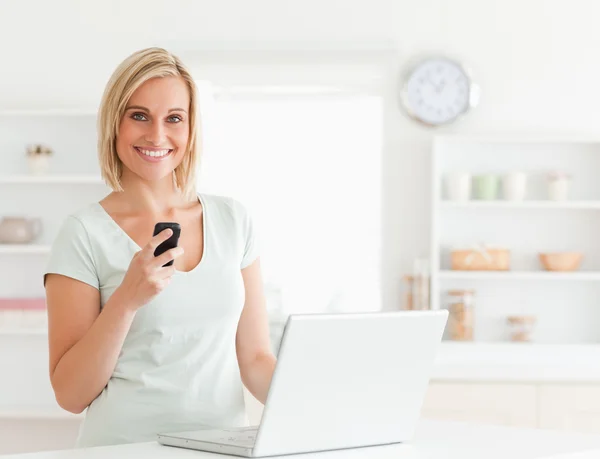 Cute woman with a mobile and a laptop looking into the camera — Stock Photo, Image