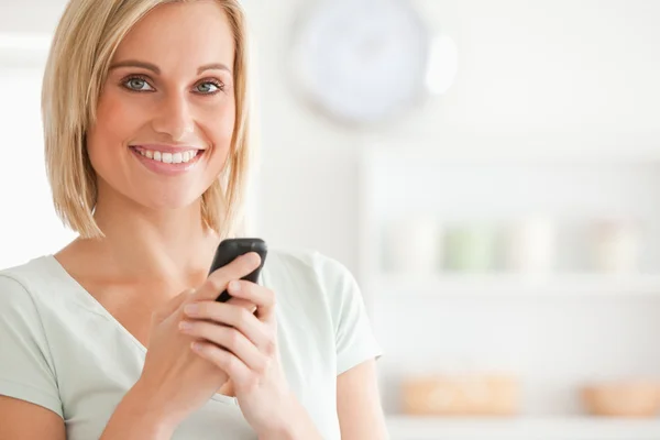Close up of a cute woman with mobile looking into the camera — Stock Photo, Image