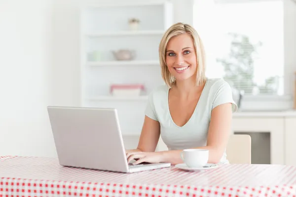 Kvinna sitter vid ett bord med kopp kaffe och anteckningsbok söker — Stockfoto