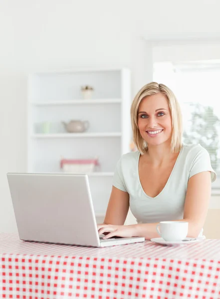 Smiling woman sitting at a table with cup of coffee and notebook — Stock Photo, Image