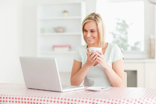 Женщина держит кофе с ноутбуком перед собой — стоковое фото