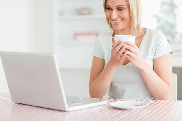 一个女人抱着咖啡，在她面前的笔记本电脑的关 — 图库照片